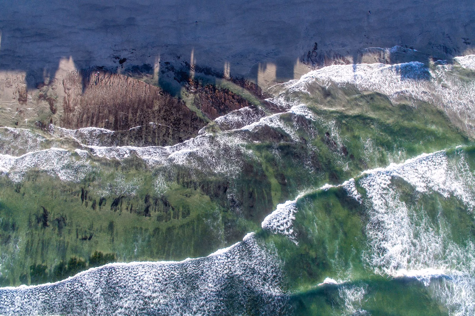 Aerial view of a coastal bluff above breaking waves on the north San Diego County coast