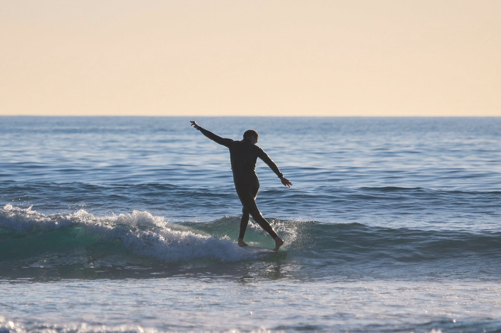 A surfer riding a small wave off Carlsbad, California